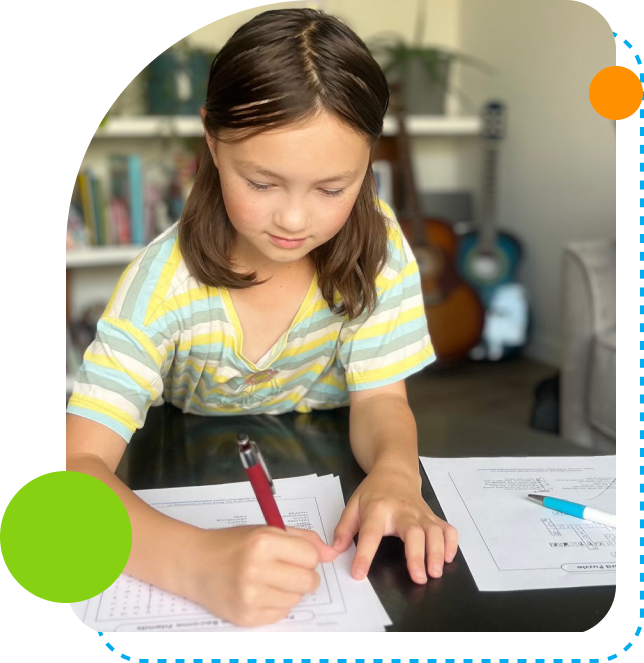 Young girl focused on writing at a desk indoors.